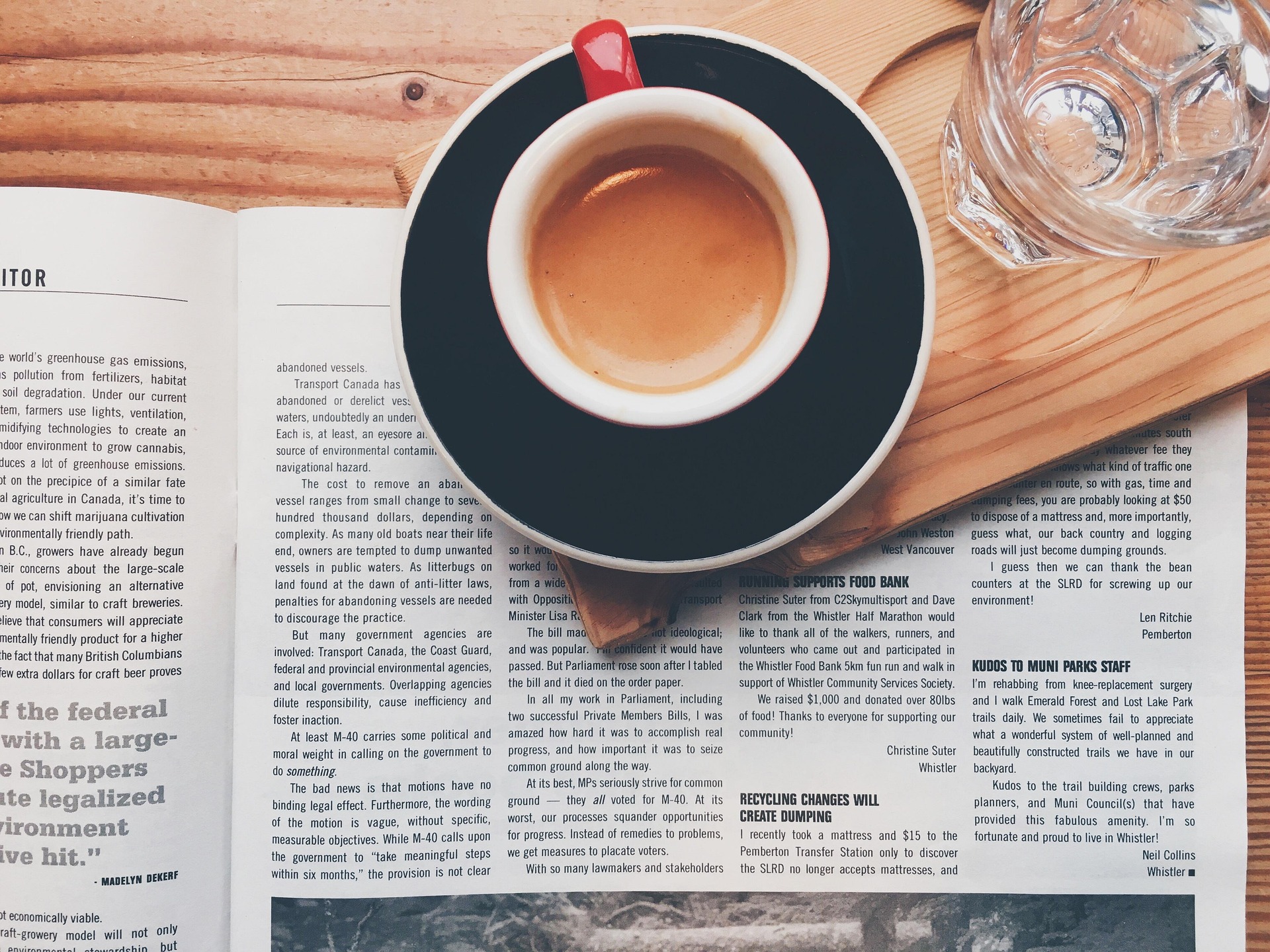 A newspaper resting next to a cup of coffee